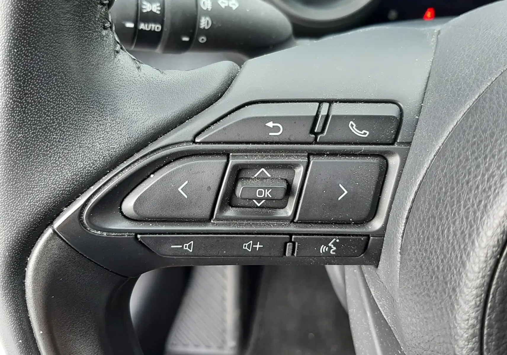 Gros plan sur les commandes multifonctions noires au volant côté gauche de la Toyota Yaris hybride 2023.