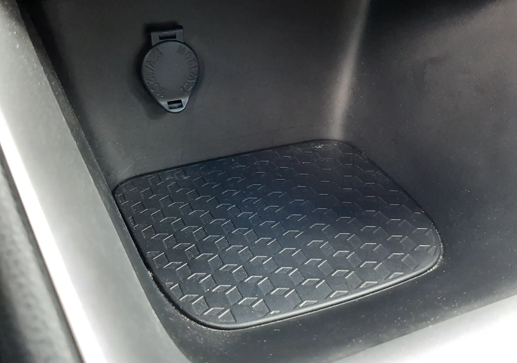 Détail de la console centrale noire de la Toyota Yaris hybride 2023 avec prise 12V et surface antidérapante.