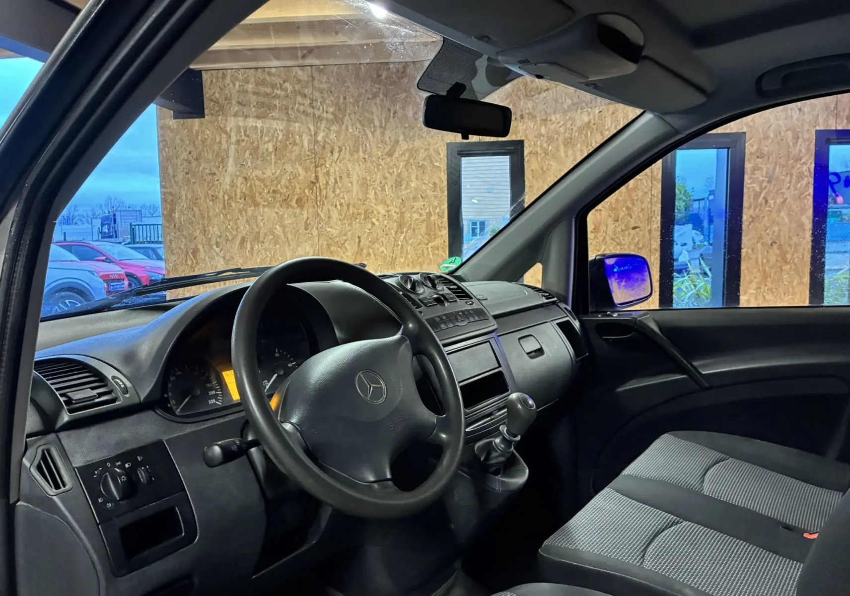 Vue intérieure côté conducteur du Mercedes Vito gris 2012, montrant le volant, tableau de bord et sièges en tissu noir.