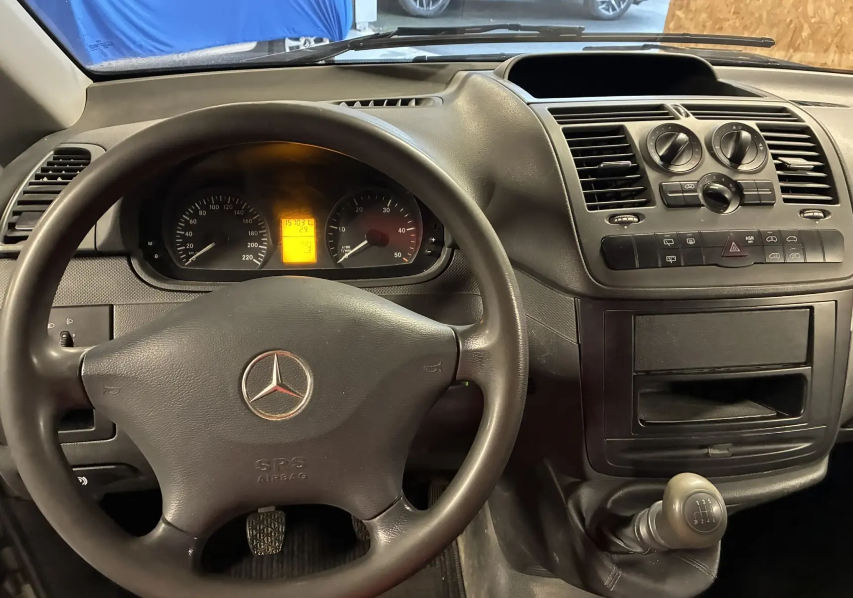 Vue intérieure du tableau de bord et volant noir d'un Mercedes Vito gris, avec levier de vitesse manuel visible.