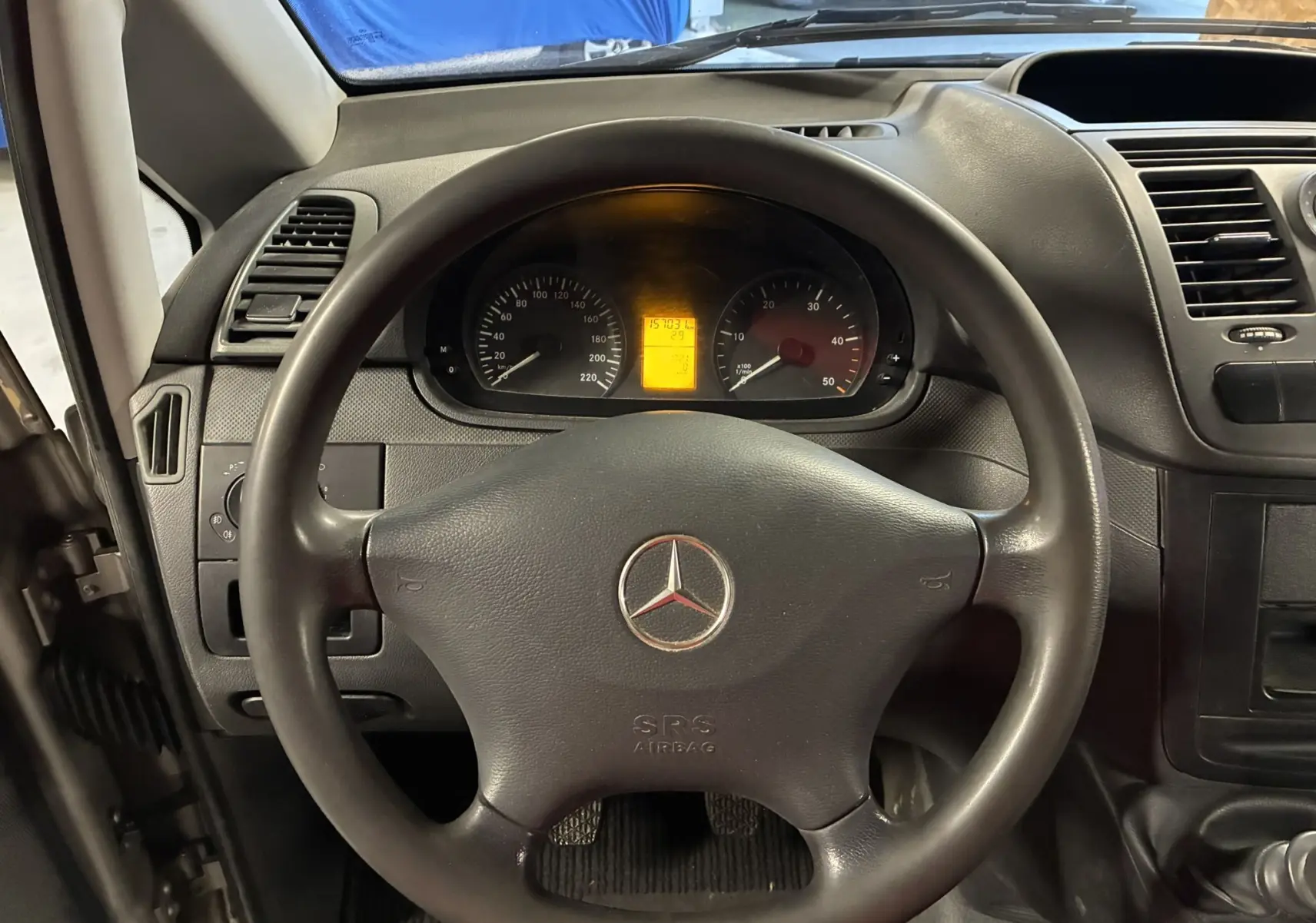 Vue intérieure centrée sur le volant noir et le tableau de bord du Mercedes Vito 2.8 113 CDI fourgon long gris de 2012.
