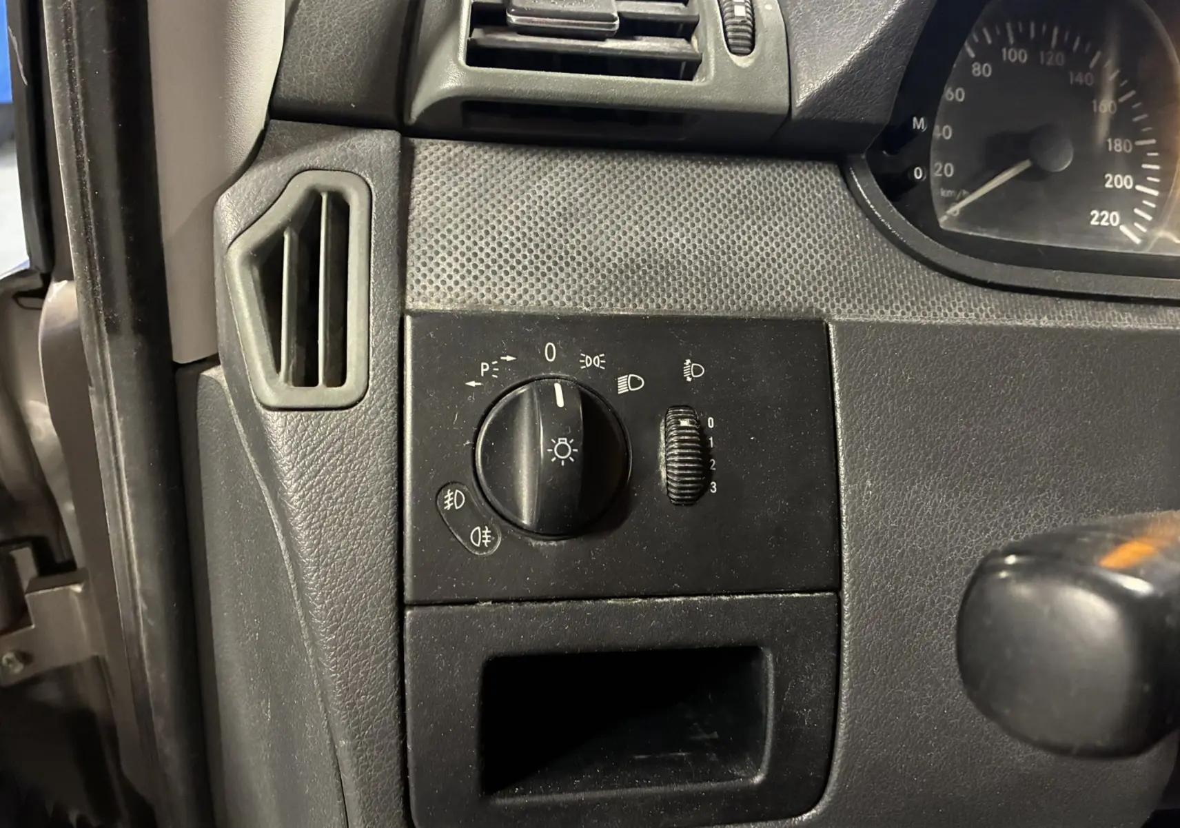 Détail du tableau de bord noir du Mercedes Vito 2.8 113 CDI gris, avec commande d’éclairage et aérateur côté gauche.