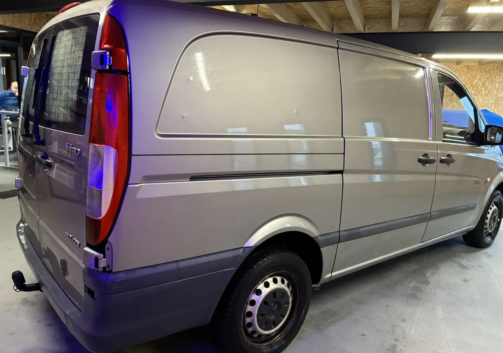 Vue 3/4 arrière droite d’un utilitaire Mercedes Vito gris 2012, fourgon long avec feux arrière verticaux et attelage.