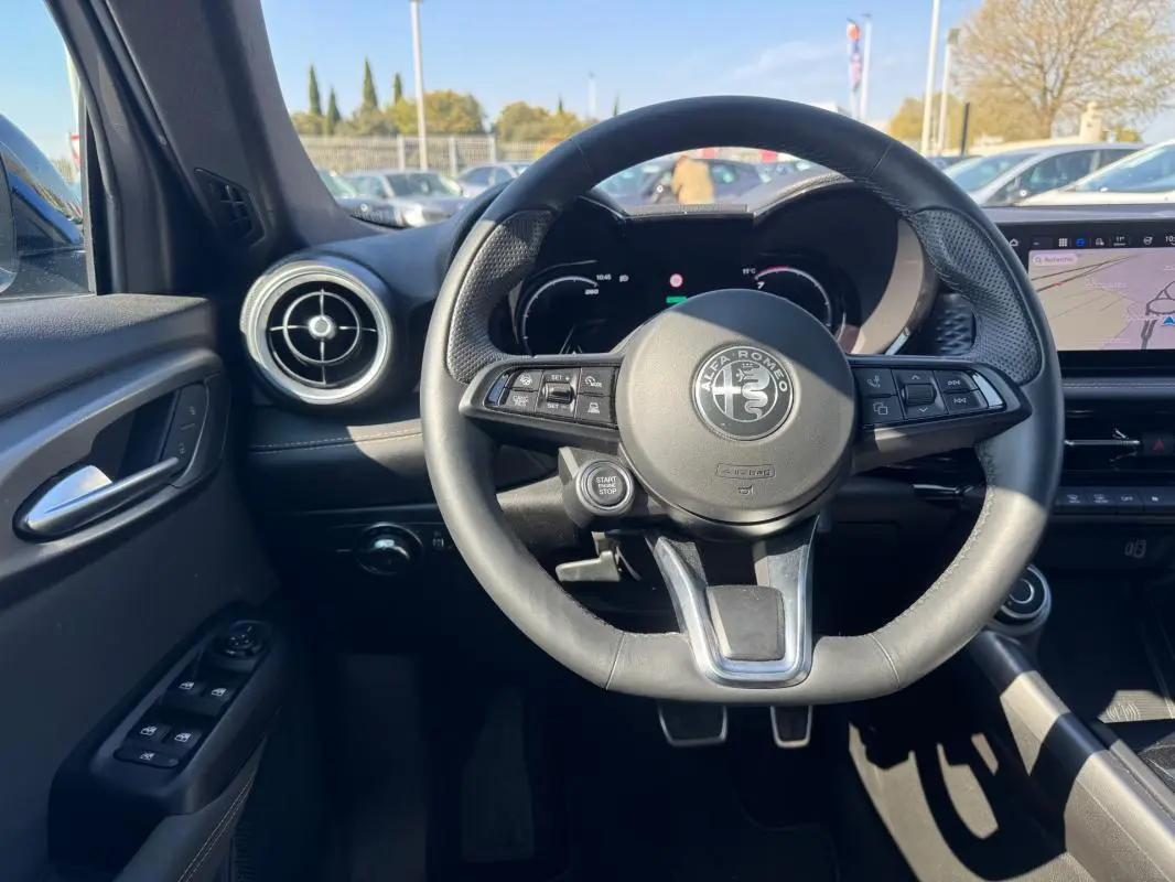 Intérieur de l'Alfa Romeo Tonale 2025, vue centrée sur le volant cuir noir avec logo Alfa Romeo et tableau de bord digital.