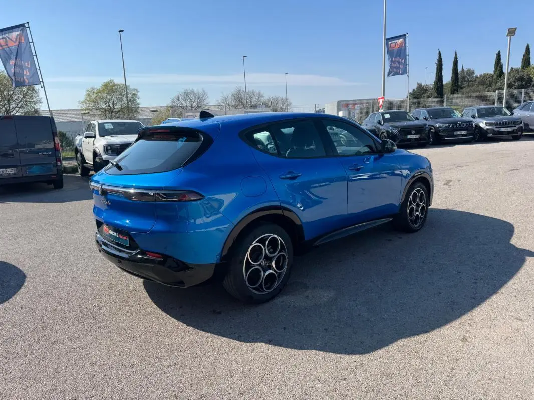 Vue 3/4 arrière droite d'une Alfa Romeo Tonale 2025 bleu foncé avec jantes distinctives à cercles entrelacés.