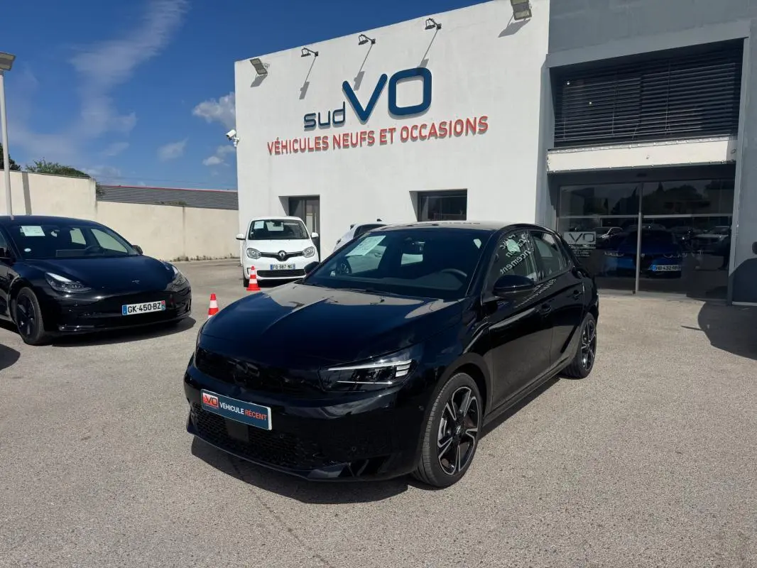 Opel Corsa 2025 noire vue en 3/4 avant droit avec jantes alliage 16 pouces, stationnée devant un concessionnaire.