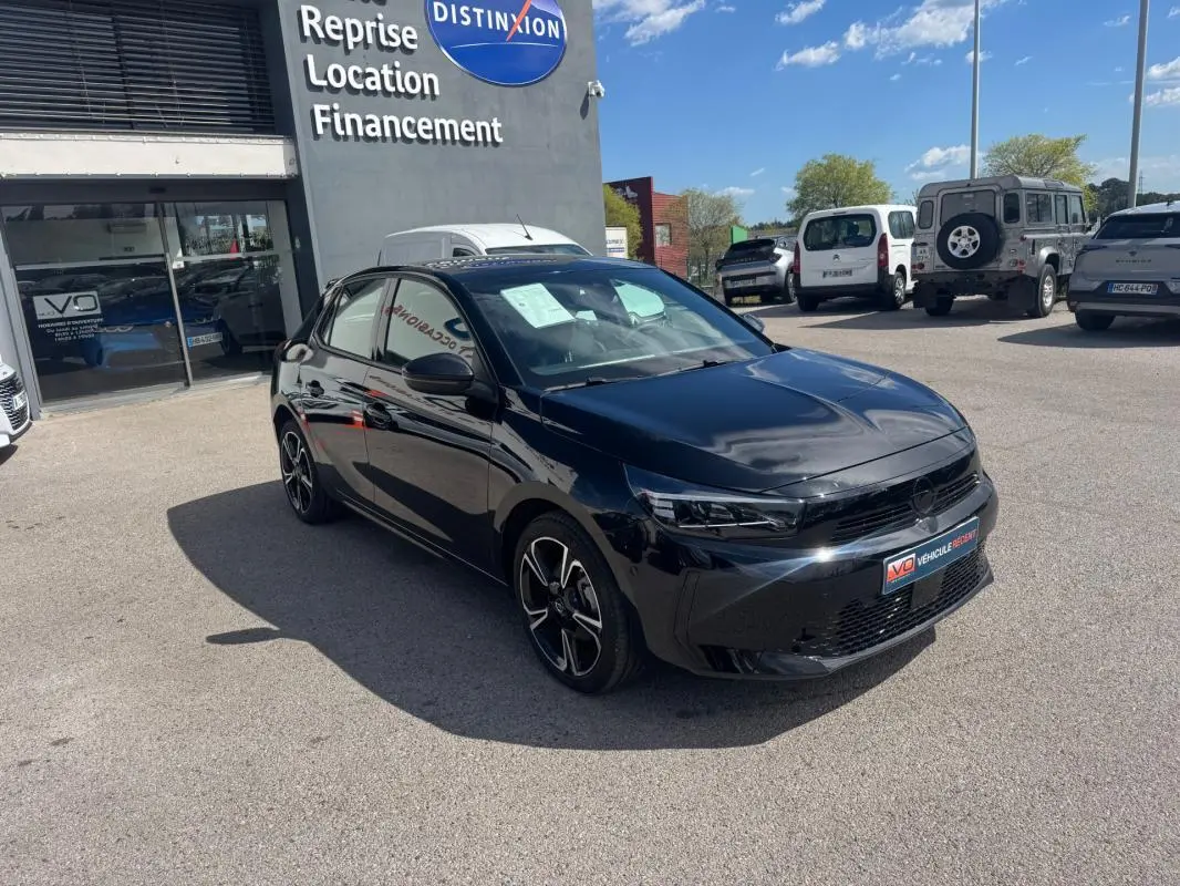 Opel Corsa noire 2025 vue 3/4 avant droit, jantes alliage 16 pouces, stationnée devant un garage.