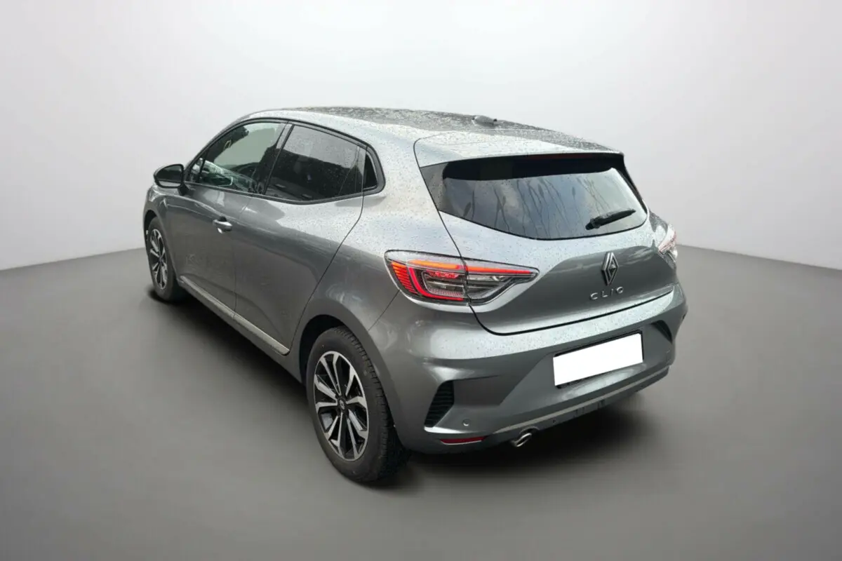 Vue 3/4 arrière droite d'une Renault Clio gris schiste 2025 avec jantes alu noires et vitres surteintées.