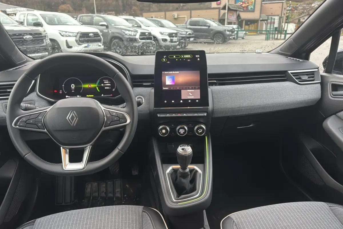Vue intérieure avant de la Renault Clio V TCe 90 Techno Plus 2025, tableau de bord moderne avec écran tactile vertical et boîte manuelle.