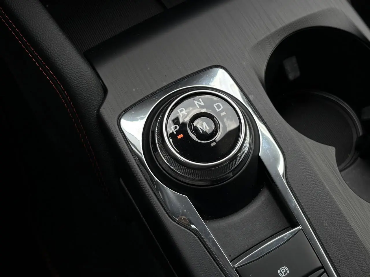 Gros plan sur le sélecteur rotatif de boîte automatique dans l’habitacle noir du Ford Kuga bleu azur 2023 finition ST-Line X.