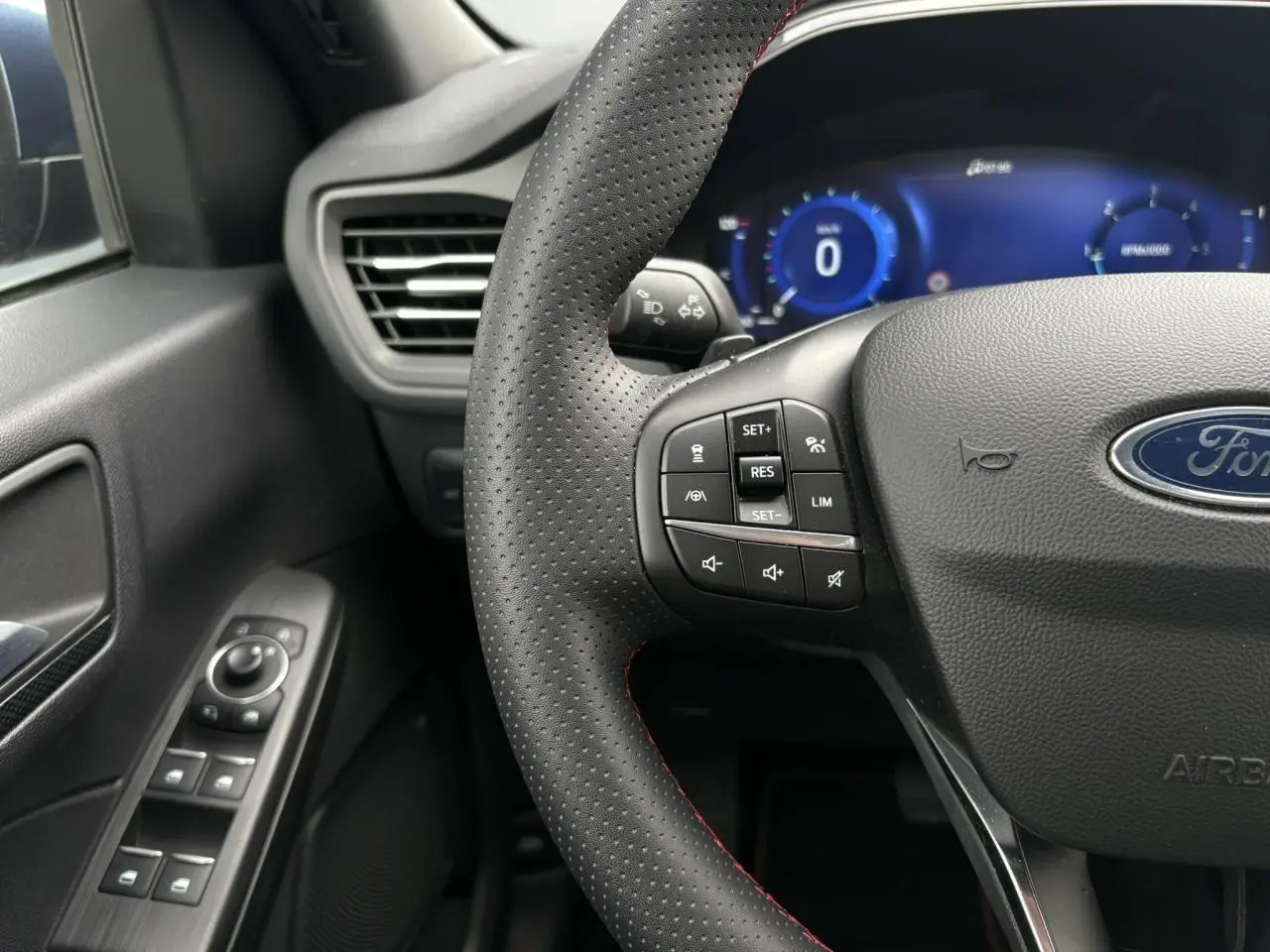 Vue rapprochée du volant perforé noir avec surpiqûres rouges et commandes multifonctions du Ford Kuga 2023.