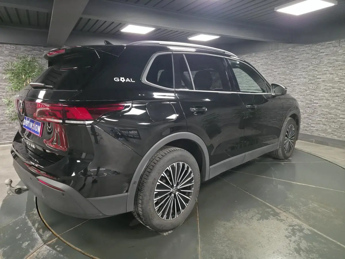 Volkswagen Tiguan noir en 3/4 arrière droit, avec jantes alliage et crochet d'attelage visible.