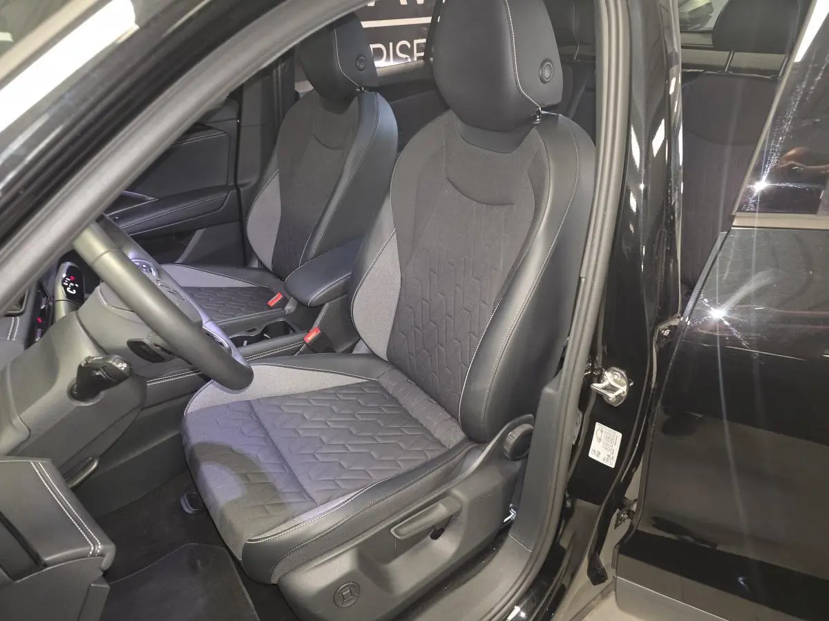 Vue intérieure côté conducteur du Volkswagen Tiguan noir 2025, mettant en valeur les sièges avant en tissu et cuir.