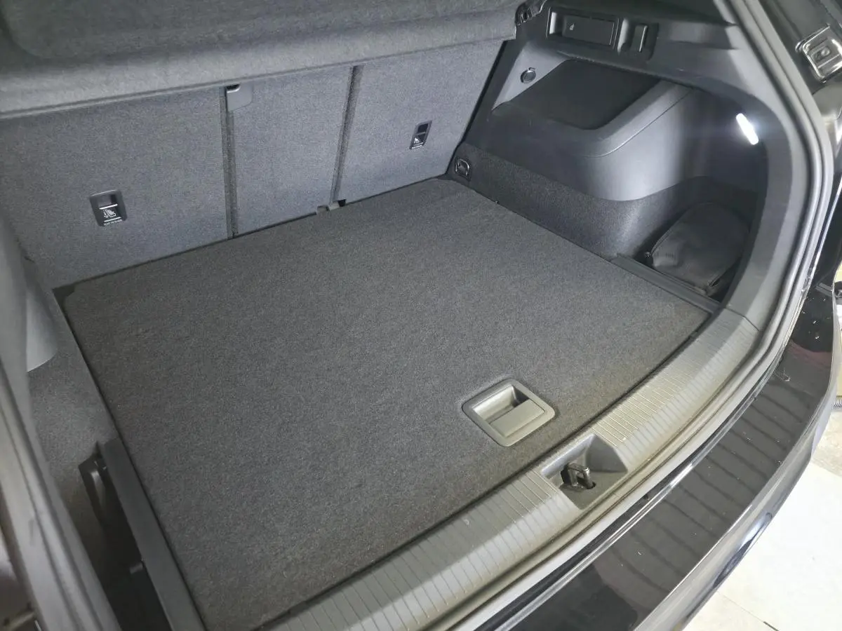Coffre spacieux du Volkswagen Tiguan noir 2025, vue intérieure arrière avec plancher plat et éclairage intégré.