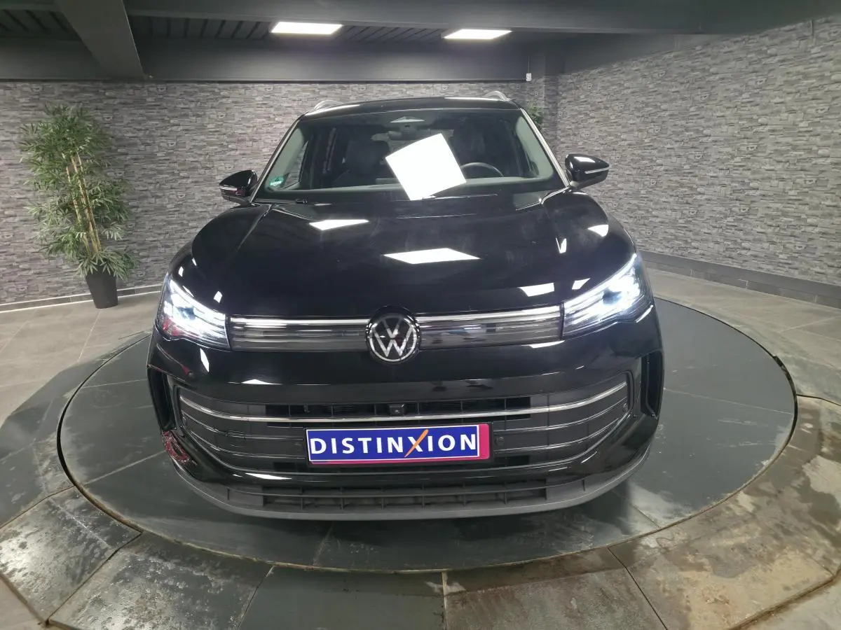 Volkswagen Tiguan noir vue de face en intérieur avec phares LED allumés et calandre chromée.