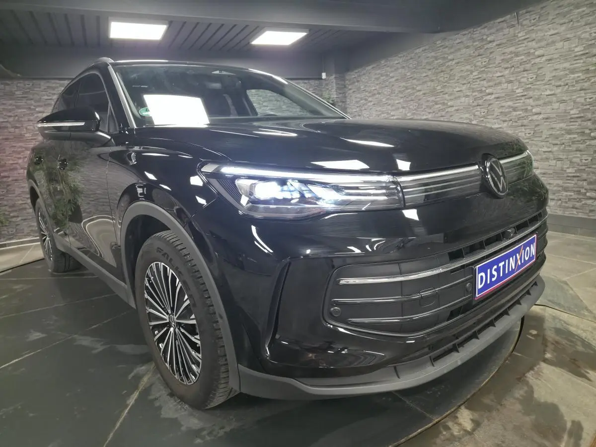 Volkswagen Tiguan noir 2025 en 3/4 avant droit avec phares LED allumés et jantes alliage distinctives.