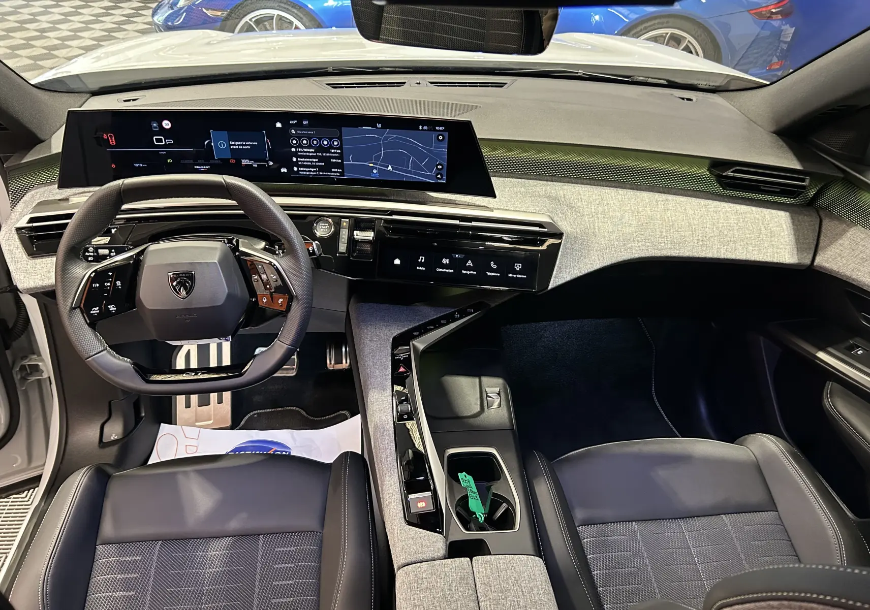 Vue intérieure avant du Peugeot 5008 Hybrid blanc 2025, tableau de bord numérique large et volant compact multifonction.