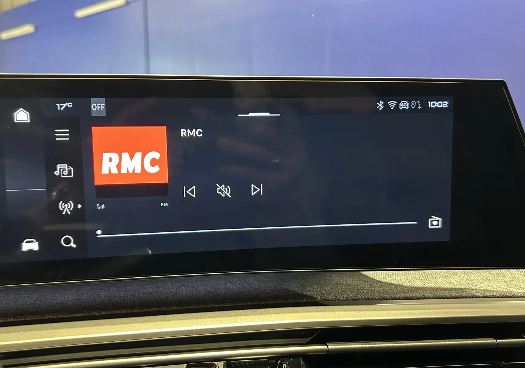 Vue intérieure du tableau de bord du Peugeot 5008 Hybrid blanc, écran tactile affichant la radio RMC.
