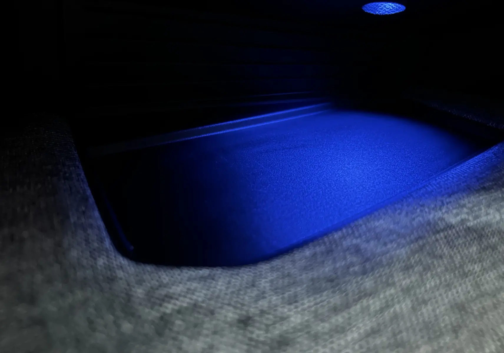 Intérieur du coffre du Peugeot 5008 Hybrid blanc 2025, éclairage bleu mettant en valeur le tapis de sol.