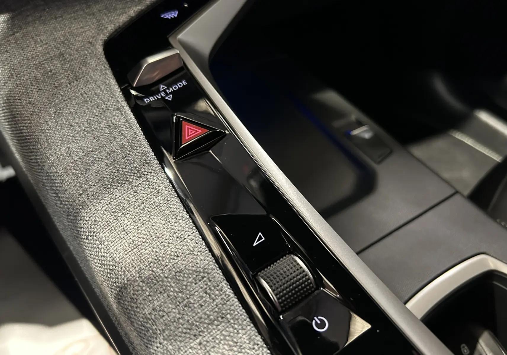 Gros plan sur la console centrale du Peugeot 5008 Hybrid 2025, montrant les boutons Drive Mode et warning sur finition noire brillante.