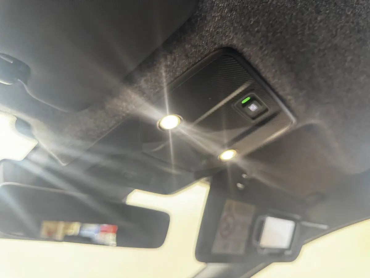 Plafonnier intérieur allumé avec miroir de courtoisie ouvert sur Renault Clio gris clair, vue vers le toit et pare-soleil.