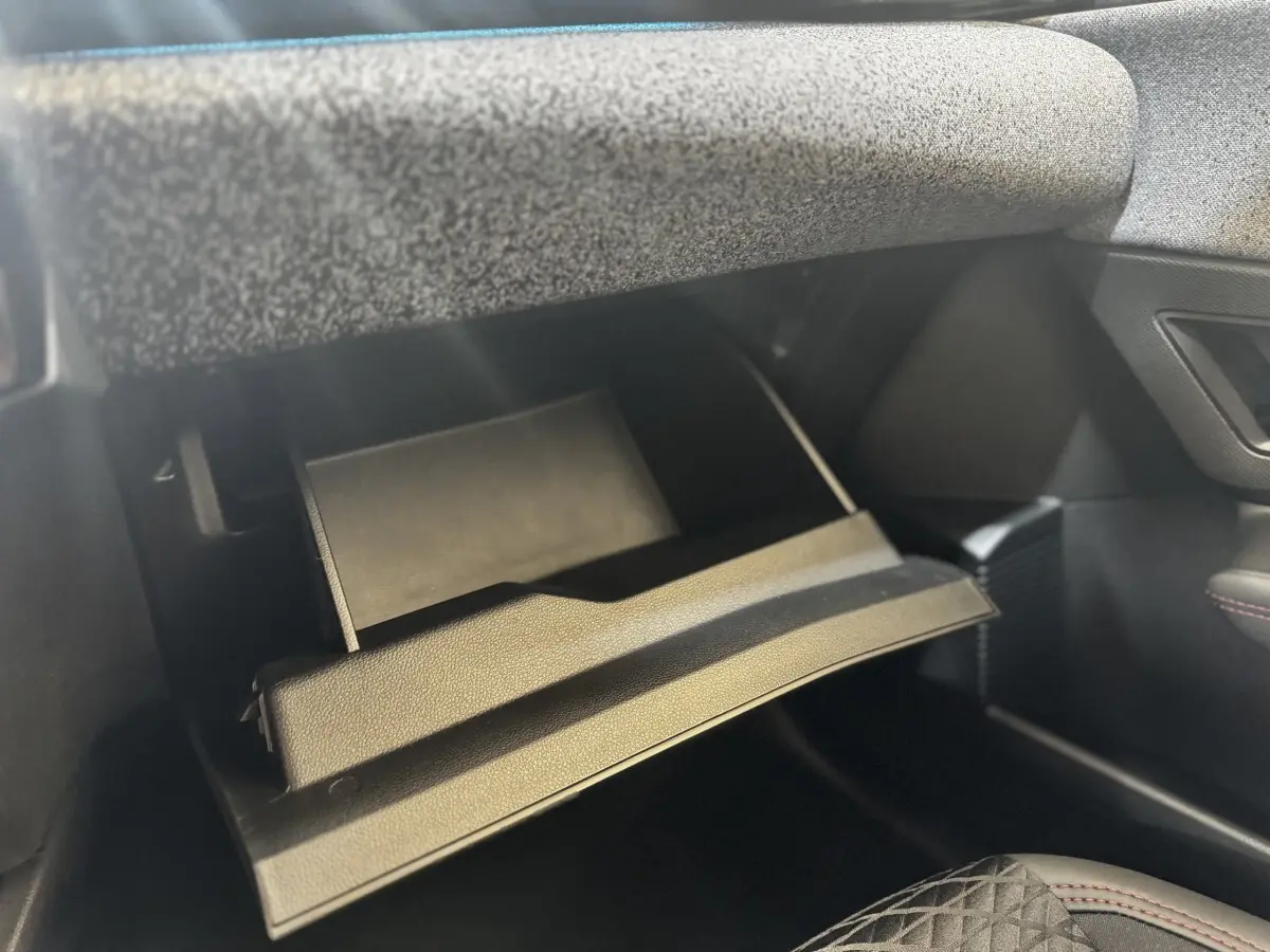 Gant de boîte à gants ouvert côté passager dans l’habitacle sombre d’une Renault Clio gris clair 2026.
