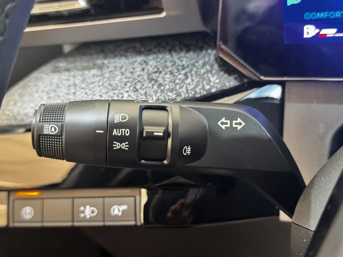 Gros plan sur la commande des feux et clignotants à gauche du volant dans l’habitacle de la Renault Clio gris clair 2026.