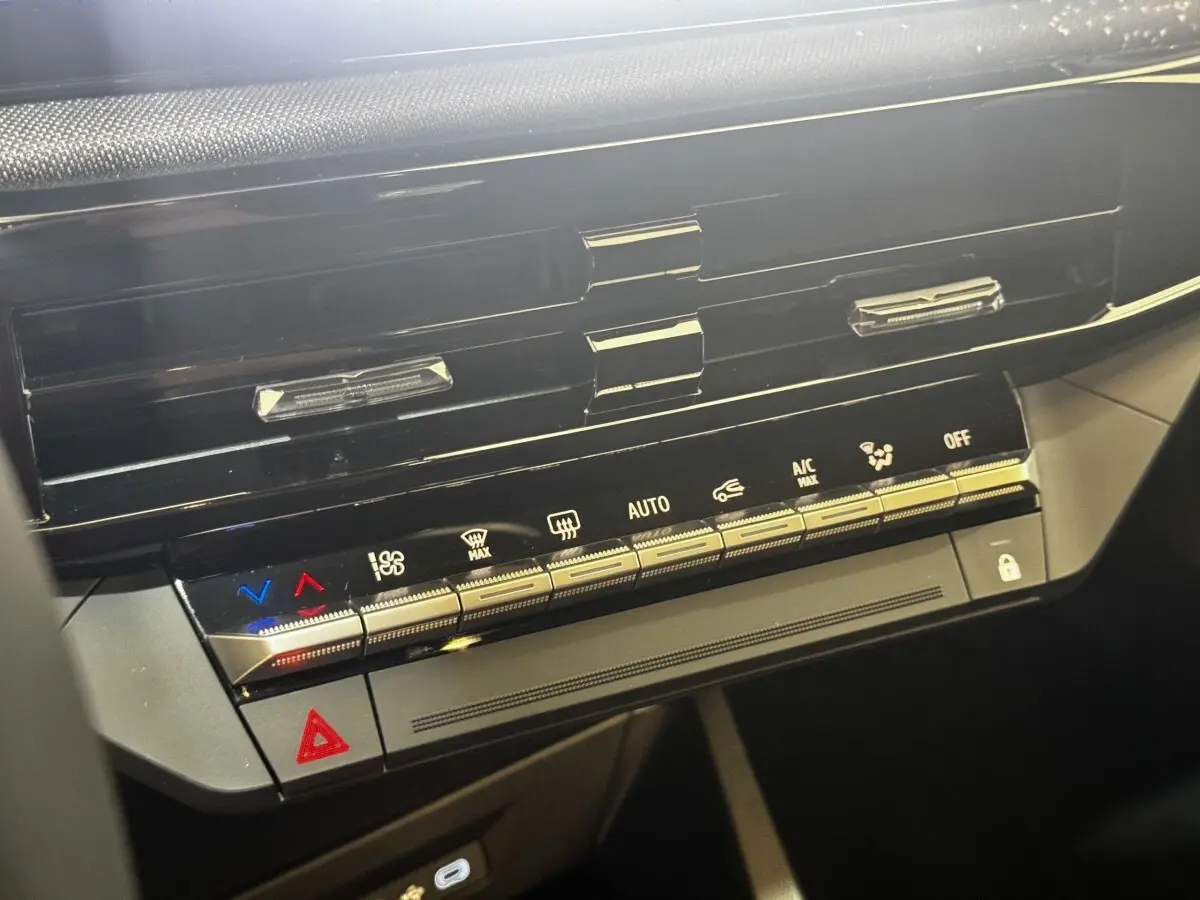 Gros plan sur la console centrale noire de la Renault Clio gris clair 2026, avec commandes climatisation et bouton hazard.
