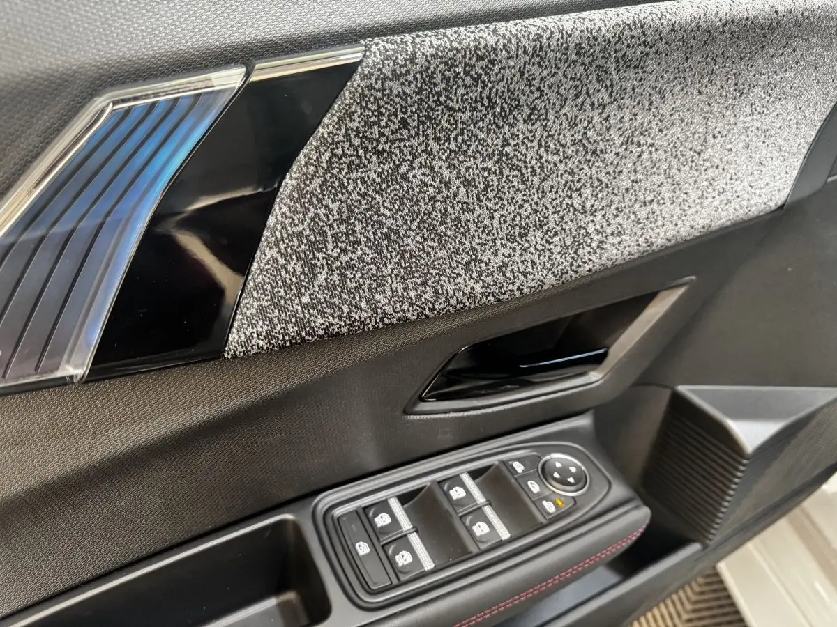 Détail de la porte intérieure côté conducteur de la Renault Clio gris clair, avec commandes électriques et tissu texturé.