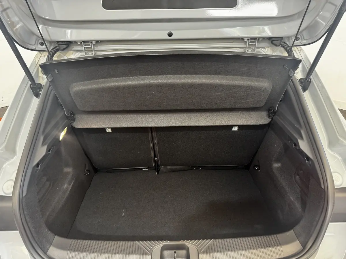 Coffre ouvert vu de l'arrière d'une Renault Clio gris clair 2026, montrant l'espace de chargement vide et la tablette de coffre.