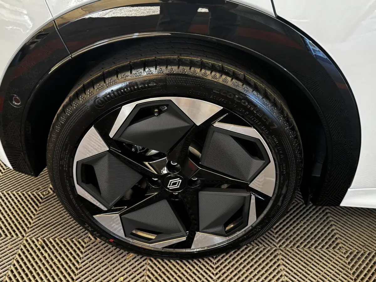 Gros plan sur la roue avant droite de la Renault Clio gris clair, jante noire et argentée au design géométrique.