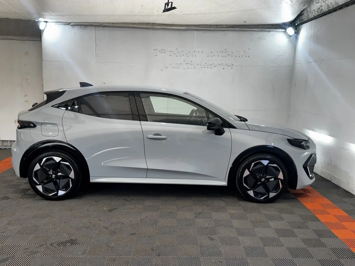 Profil droit de la Renault Clio Techno TCe 115 gris clair 2026 avec jantes noires et rétroviseurs rabattables électriques.