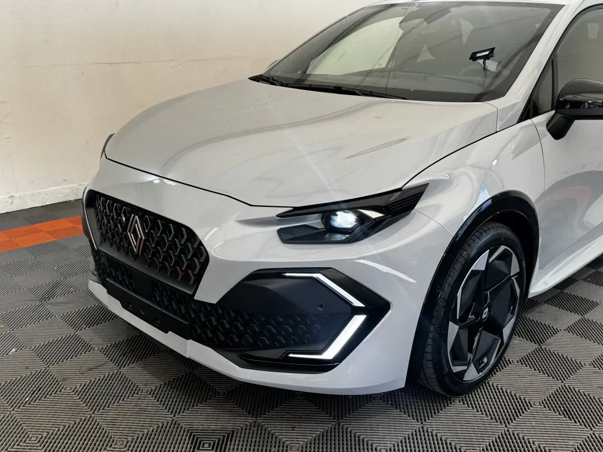 Vue 3/4 avant droit d'une Renault Clio Techno TCe 115 gris clair avec phares LED et jantes noires distinctives.
