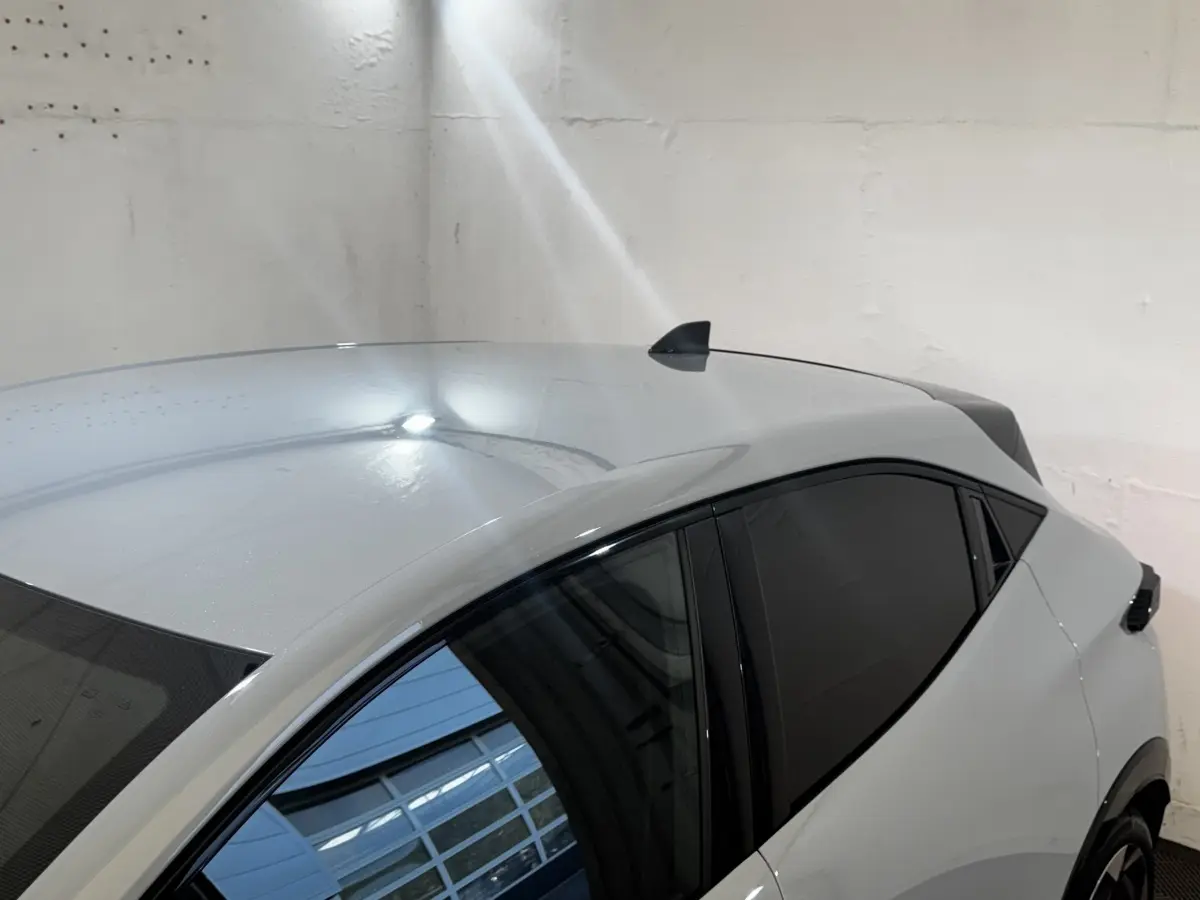 Vue de dessus côté droit d'une Renault Clio gris clair avec vitres teintées et antenne requin.