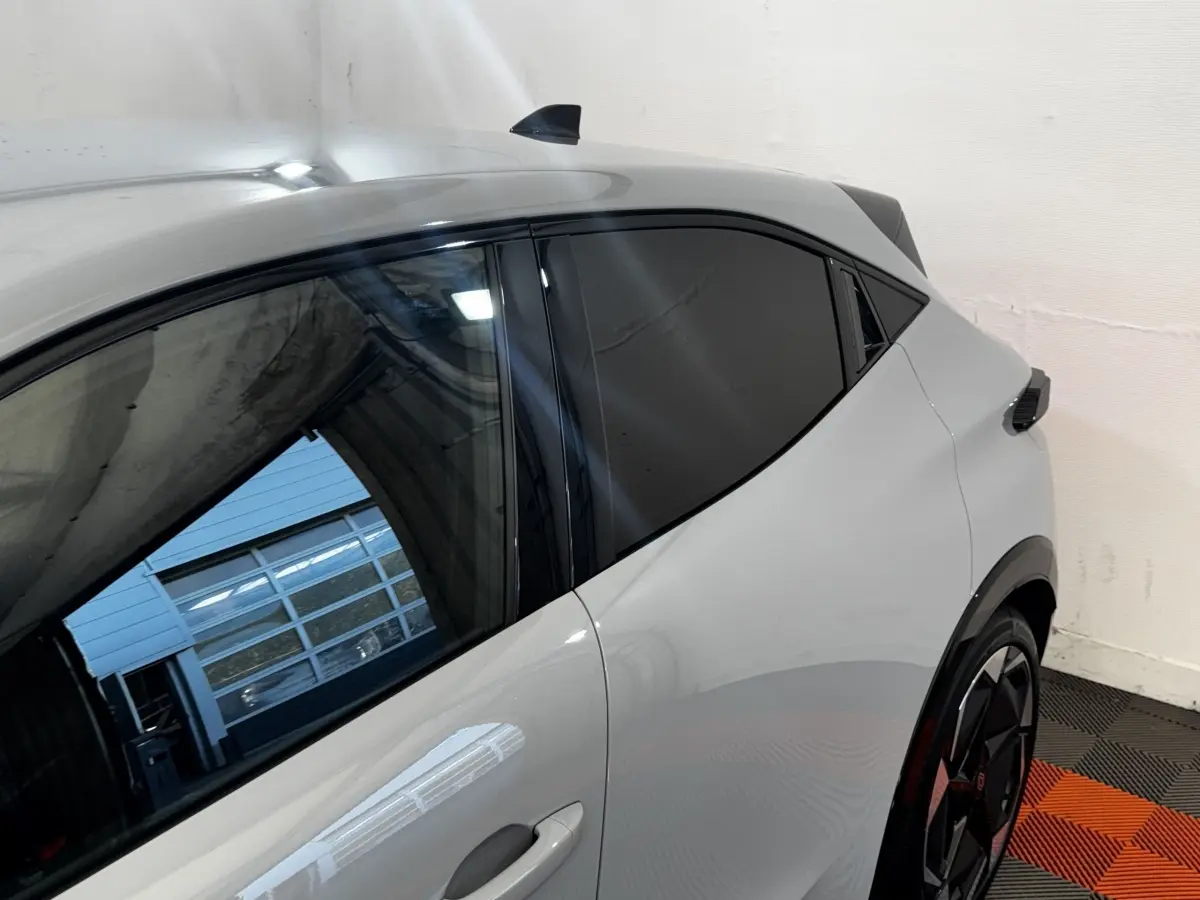 Vue latérale gauche rapprochée de la Renault Clio Techno TCe 115 gris clair avec vitres teintées et jantes noires.