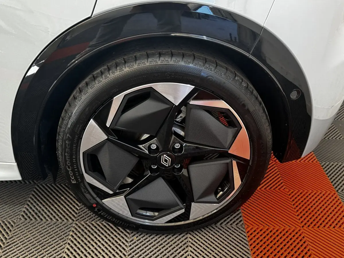 Gros plan sur la roue avant droite d’une Renault Clio gris clair, jante noire et argentée au design géométrique.