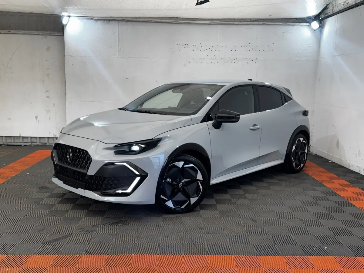 Renault Clio Techno TCe 115 gris clair vue 3/4 avant droit, avec jantes noires et phares LED allumés.