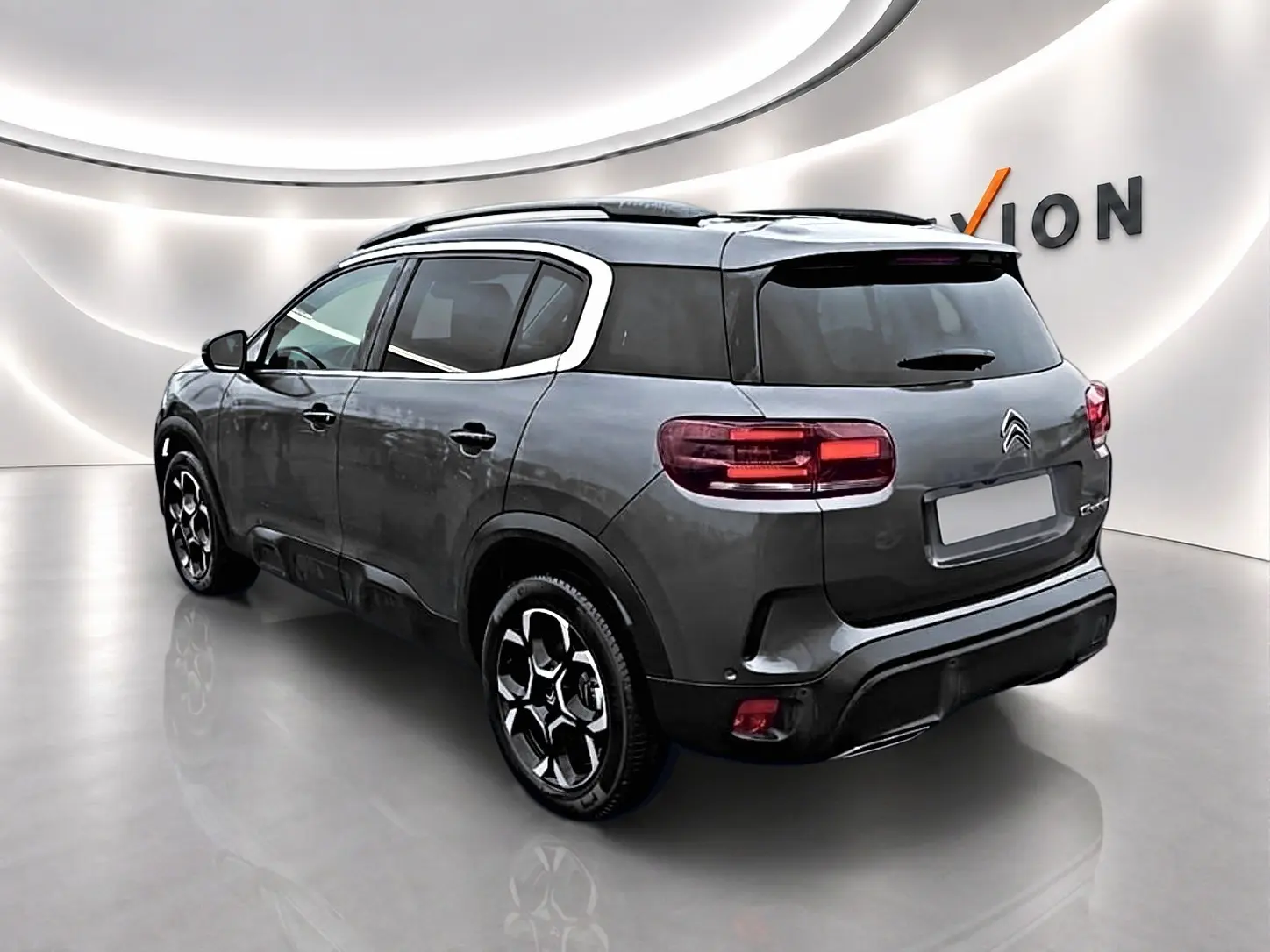 Citroën C5 Aircross gris vue 3/4 arrière droit, avec barres de toit et jantes alliage distinctives.