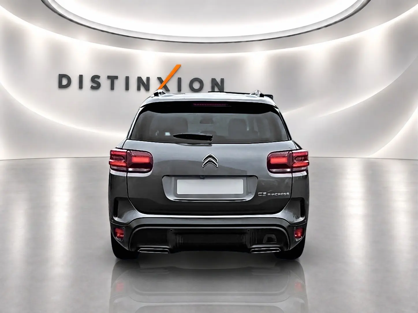 Vue arrière d'un Citroën C5 Aircross gris 2025 avec feux LED et barres de toit en showroom lumineux.