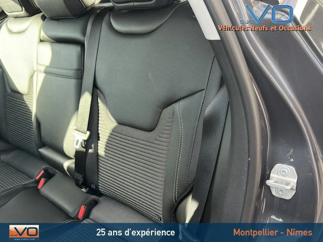 Vue rapprochée du siège arrière droit en cuir noir du Jeep Compass gris 2024 avec ceinture de sécurité visible.