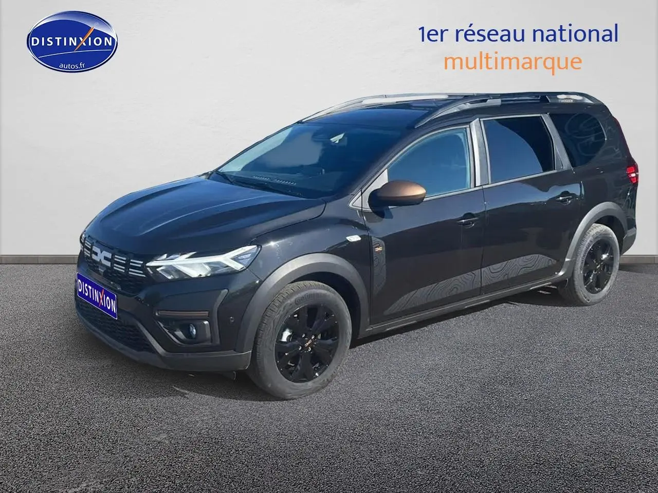 Dacia Jogger noir nacré en 3/4 avant droit, avec barres de toit et jantes alu noires brillantes.