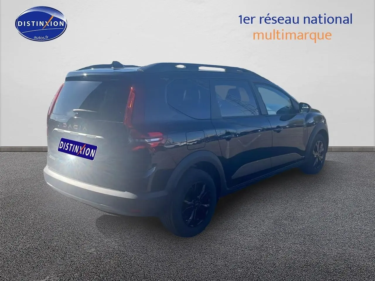 Vue 3/4 arrière droite d'un Dacia Jogger noir nacré avec barres de toit et jantes alu noires.