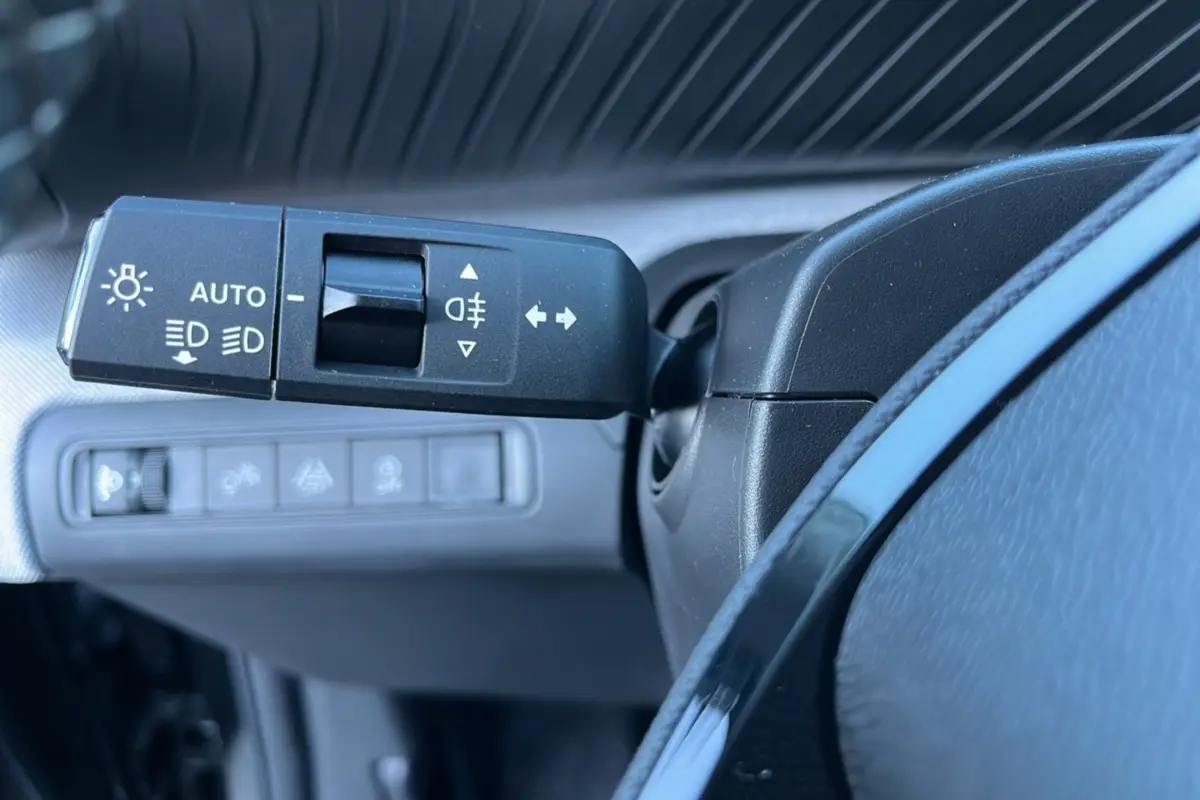 Gros plan sur la commande des feux et clignotants à gauche du volant cuir dans le tableau de bord noir du Citroën C3 Aircross 2025.