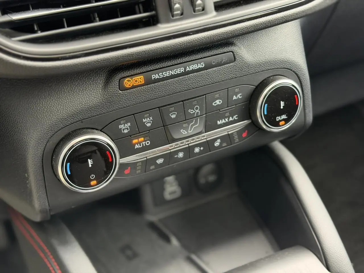 Gros plan sur la console centrale du Ford Kuga 2023, montrant les commandes de climatisation automatique bi-zone et sièges chauffants.