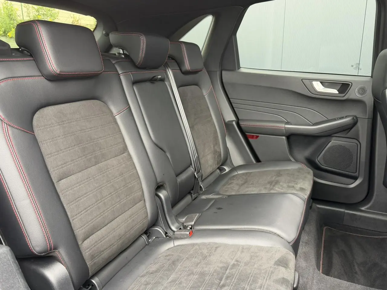 Vue latérale droite de la banquette arrière en cuir noir et alcantara avec surpiqûres rouges du Ford Kuga 2023.