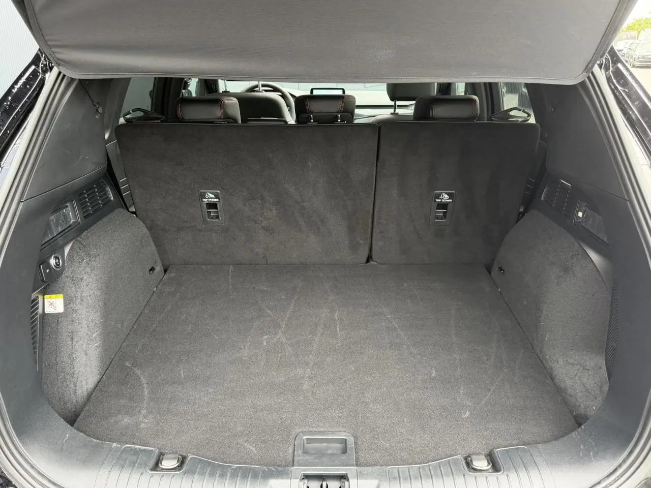 Coffre ouvert vu de l'arrière d'un Ford Kuga noir Agathe, montrant l'espace de chargement et la banquette arrière relevée.