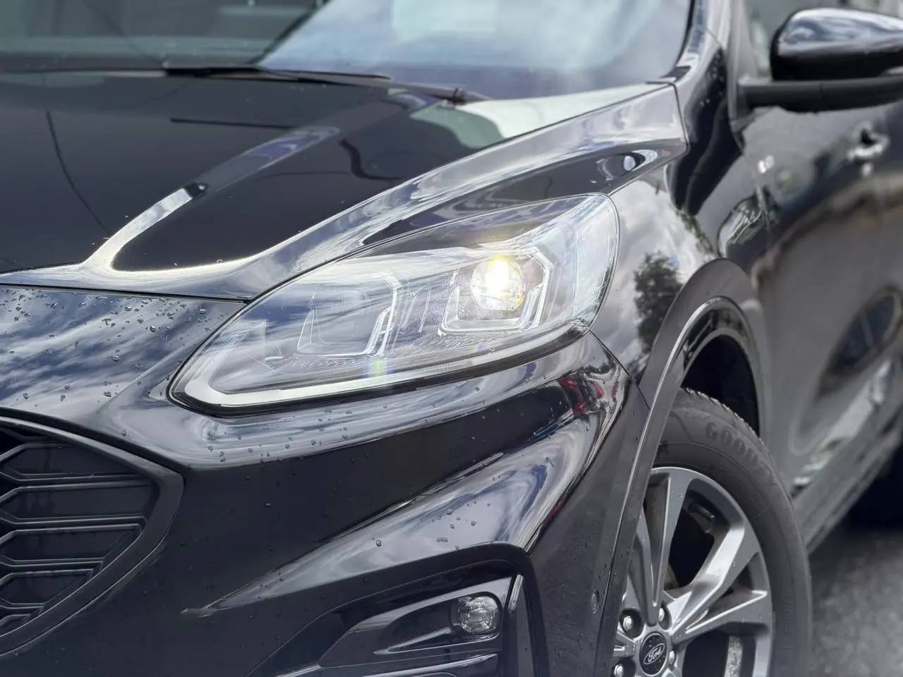 Vue 3/4 avant droit du Ford Kuga noir Agathe avec phares LED allumés et jantes alliage 18 pouces ST-Line.