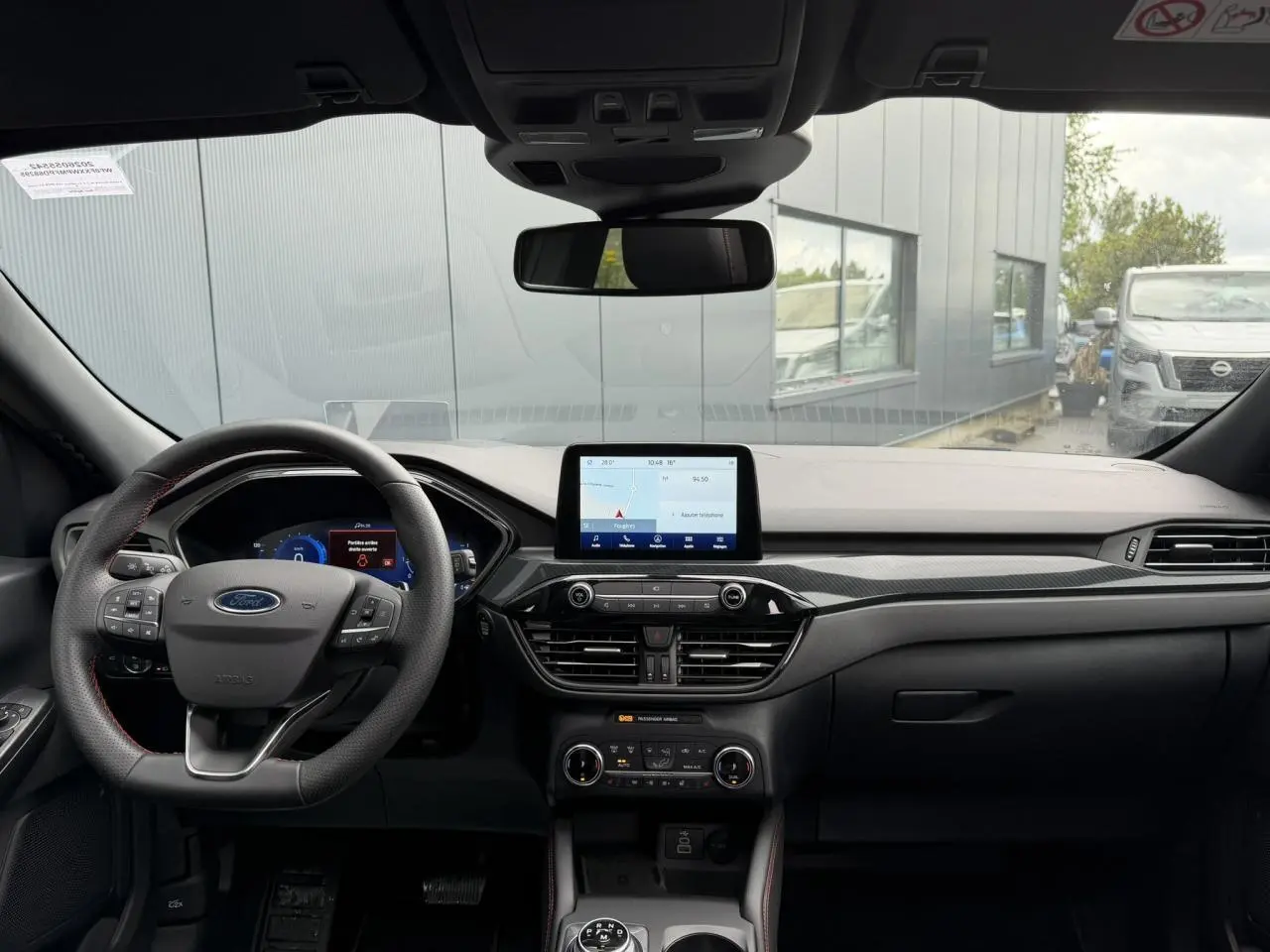 Vue frontale intérieure du Ford Kuga 2.0 EcoBlue 120 BVA ST-Line X 2023, tableau de bord noir avec écran tactile central.