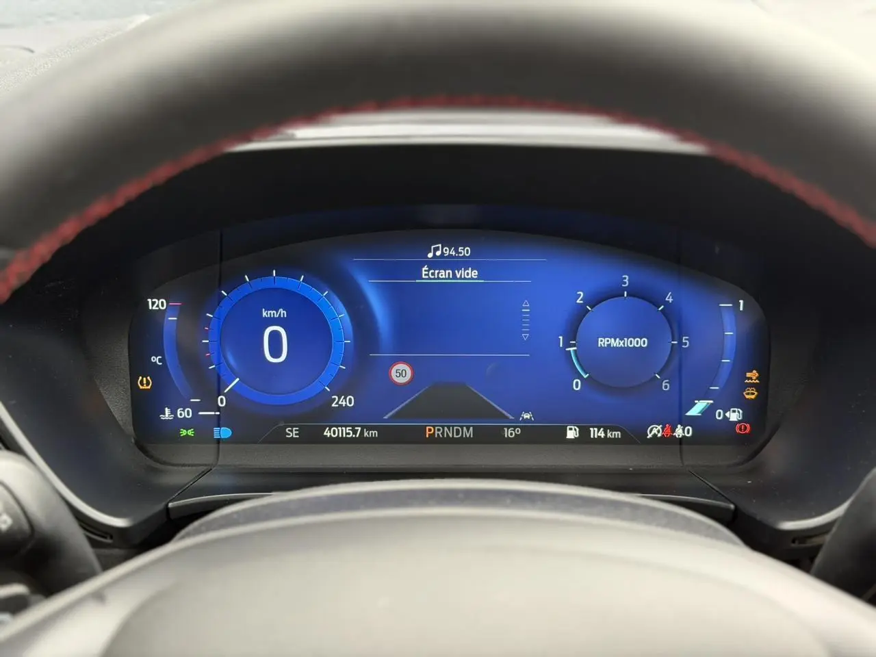 Vue rapprochée du combiné d'instrumentation numérique bleu du Ford Kuga noir, affichant vitesse et compte-tours.