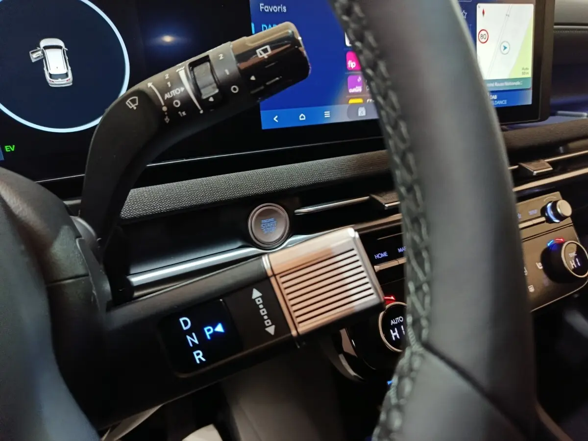 Gros plan intérieur sur le volant cuir et la commande de boîte auto du Hyundai Tucson 1.6 Hybrid gris foncé, avec écran tactile en arrière-plan.